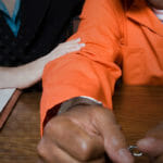 attorney sitting next to handcuffed man