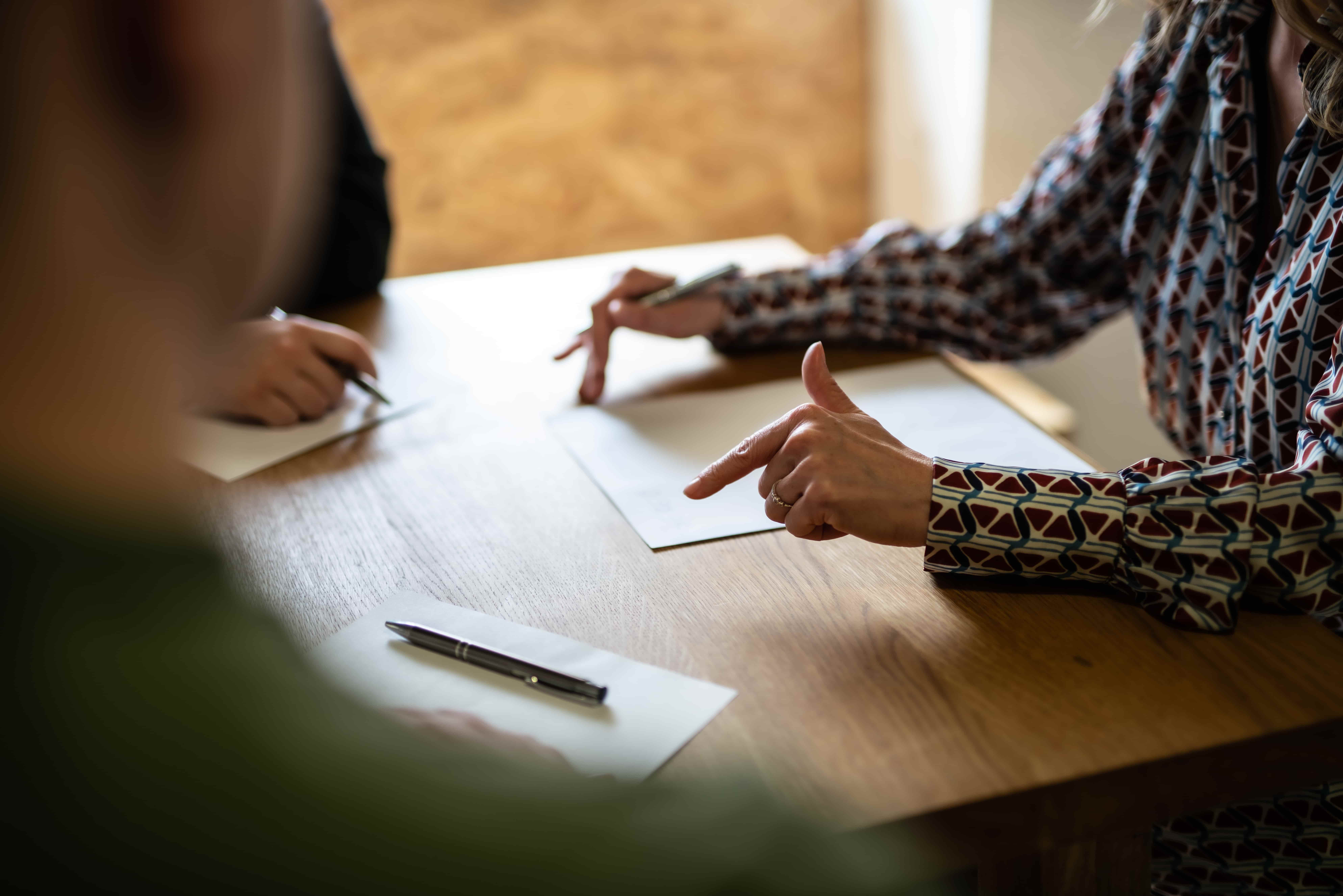 People reviewing and pointing at documents during a legal consultation or contract signing at a table.