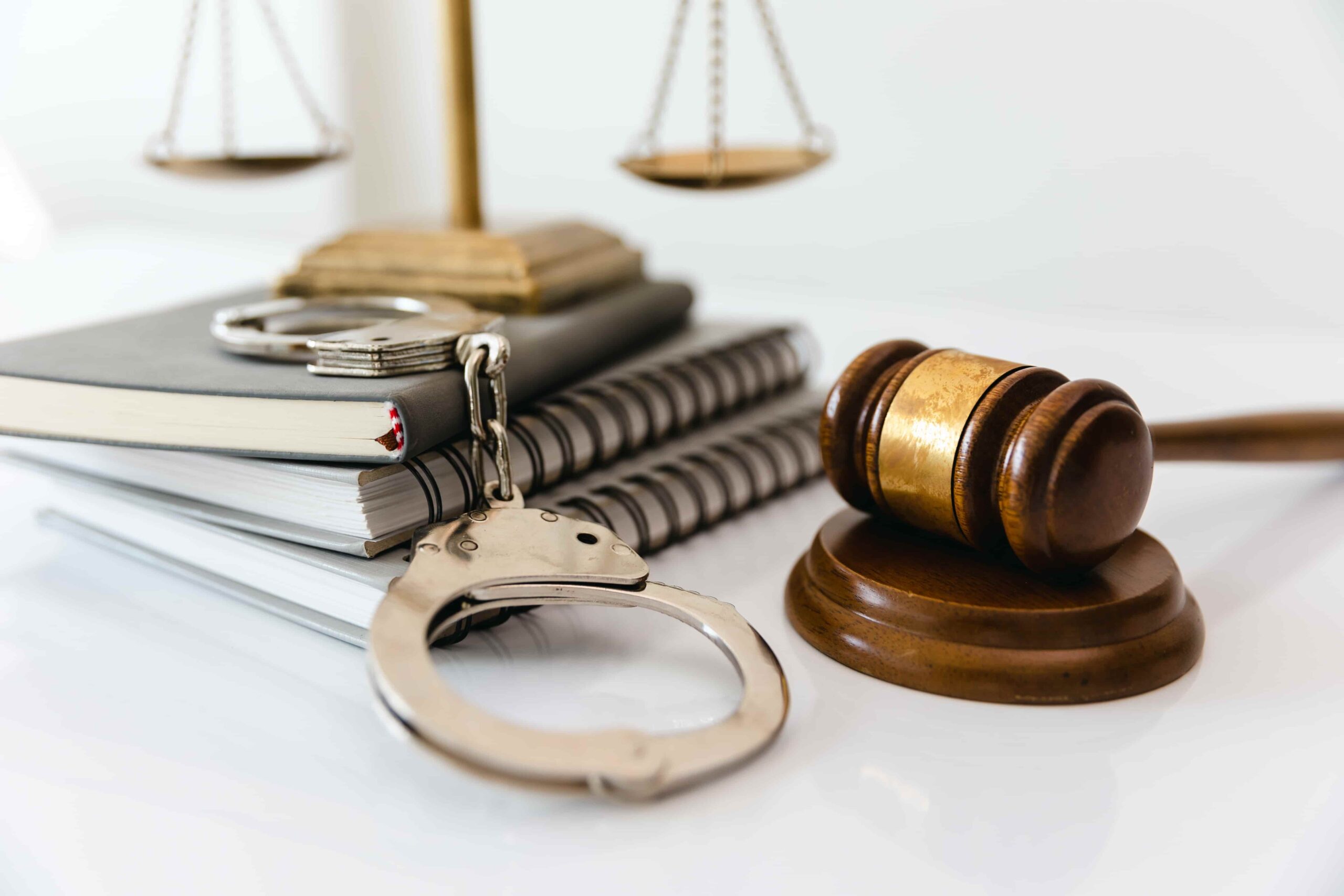 Judge’s gavel, handcuffs, law books, and scales of justice on a desk, symbolizing criminal law and the legal justice system.