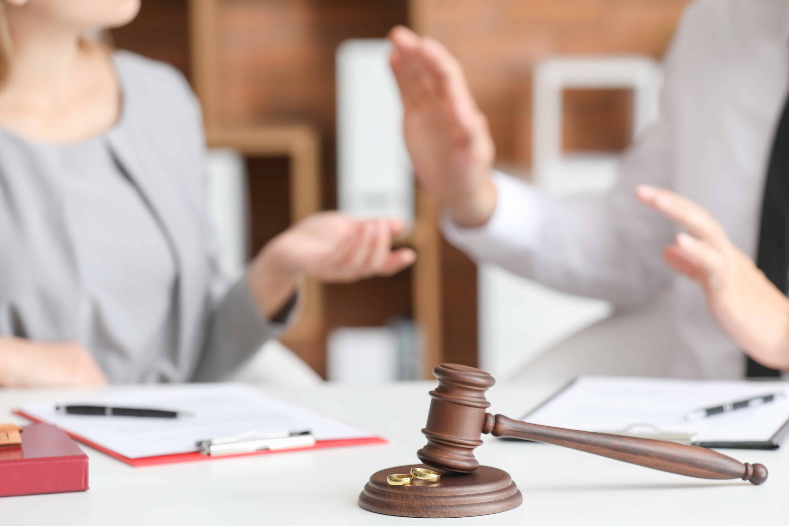 Legal dispute or negotiation with a judge’s gavel on a desk while parties argue during a legal consultation